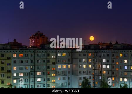 Windows, tetti e facciata di una massa di edifici di appartamenti in Russia durante la luna piena notte. Foto Stock