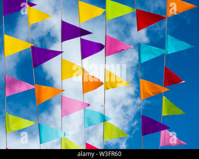 Bunting colorati bandiere contro il cielo blu nel villaggio Spagnolo durante la fiesta locale. Foto Stock