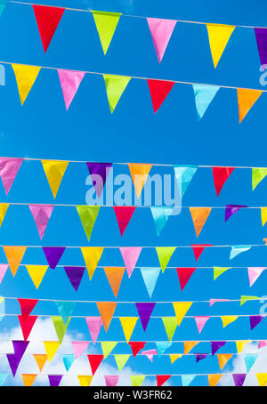 Bunting colorati bandiere contro il cielo blu nel villaggio Spagnolo durante la fiesta locale. Foto Stock