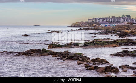 Costa rocciosa vicino a 40 piedi a Sandycove, Irlanda con Muglins faro a distanza Foto Stock