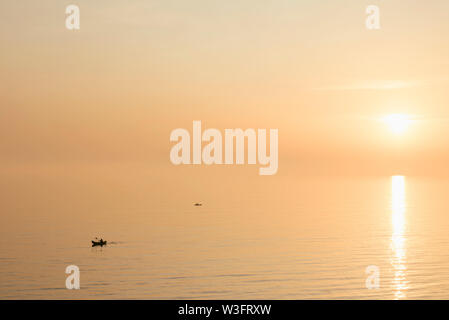 Silhouette di kayak sul mare con il sole in background Foto Stock