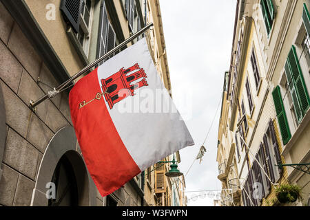 Gibilterra, Regno Unito. Bandiera di Gibilterra sventolando da una delle case in via principale. Un British Overseas territorio contestato dalla Spagna Foto Stock