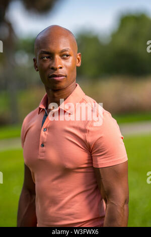 Ritratto di un bel americano africano uomo calvo che indossa un rosa polo shirt Foto Stock