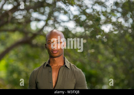 Headshot ritratto di un bel americano africano o giamaicano modello maschile che pongono in una scena del parco Foto Stock