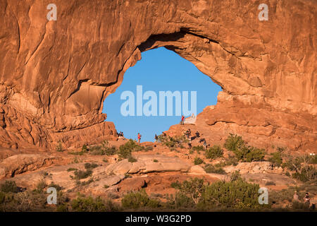I turisti nel foro di roccia a 'windows' - tardo pomeriggio Arches National Park - Utah Foto Stock