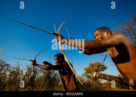 Cacciatori boscimani con arco e frecce che simula una battuta di caccia a Grashoek, Namibia Foto Stock