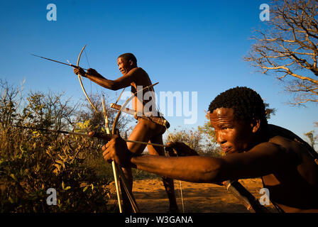 Cacciatori boscimani con arco e frecce che simula una battuta di caccia a Grashoek, Namibia Foto Stock