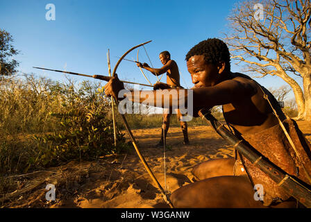 Cacciatori boscimani con arco e frecce che simula una battuta di caccia a Grashoek, Namibia Foto Stock