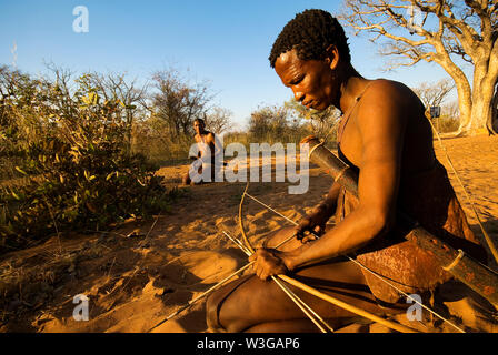 Cacciatori boscimani con arco e frecce che simula una battuta di caccia a Grashoek, Namibia Foto Stock