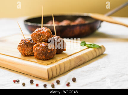 Le polpette di carne in salsa di pomodoro su una tavola di legno contro uno sfondo bianco Foto Stock