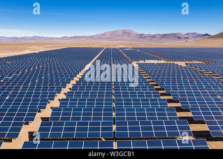 Vista aerea di centinaia di moduli di energia solare o file di pannelli lungo le terre asciutte nel deserto di Atacama, Cile. Enorme impianto fotovoltaico nel deserto Foto Stock