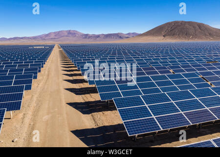 Vista aerea di centinaia di moduli di energia solare o file di pannelli lungo le terre asciutte nel deserto di Atacama, Cile. Enorme impianto fotovoltaico nel deserto Foto Stock