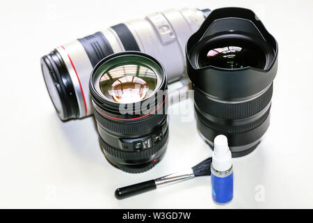 Lenti della fotocamera sul display da Canon 100-400mm teleobiettivo con zoom di Tamron 15-30mm ultra grandangolo con kit di pulizia su sfondo bianco Foto Stock