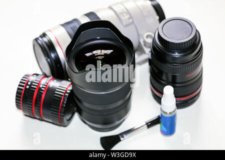 Lenti della fotocamera sul display da Canon 100-400mm teleobiettivo con zoom di Tamron 15-30mm ultra grandangolo con kit di pulizia su sfondo bianco Foto Stock