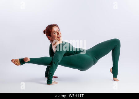 Bella slim donna in tute sportive fare yoga, stando in piedi in un asana posa di bilanciamento - collegamento di postura bianco su sfondo isolato. Il conc Foto Stock