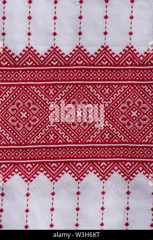 Particolare del fregio ricamato con fili rossi sul tessuto bianco, folk ucraini ricamo, vicino. Vestiti nazionali dell'Ucraina Foto Stock