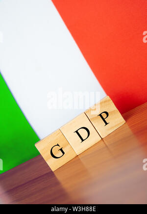 Il prodotto interno lordo o PIL dell'Italia nel blocco di legno lettere su tavola, bandiera dell'Italia come sfondo Foto Stock