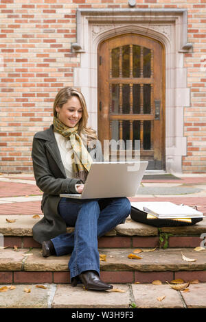 Bella e felice, sorridente, donna femmina college universitario degli studenti che studiano utilizzando computer portatile sul campus della scuola Foto Stock