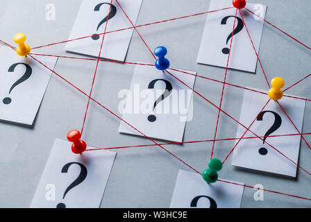 Rete di stampati punti interrogativi sulle carte bianche segnato con il pollice rampini e uniti da una stringa in una immagine concettuale Foto Stock