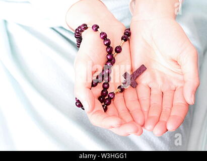 Donna che prega insieme a mano protesa con il crocifisso e il rosario croce immagine stock e stock photo Foto Stock