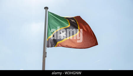 Saint Kitts e Nevis bandiera, simbolo nazionale sventolare contro il cielo blu chiaro, giornata di sole Foto Stock