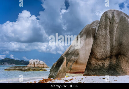 Anse Source d'Argent -enormi massi di granito sulla spiaggia sabbiosa tropicale contro il cielo blu con nuvole bianche. La Digue Island, Seicelle Foto Stock