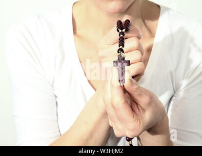 Donna che prega insieme a mano protesa con il crocifisso e il rosario croce immagine stock e stock photo Foto Stock