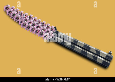 Acciaio coltello butterfly con fiore viola su un giallo background creativo Foto Stock