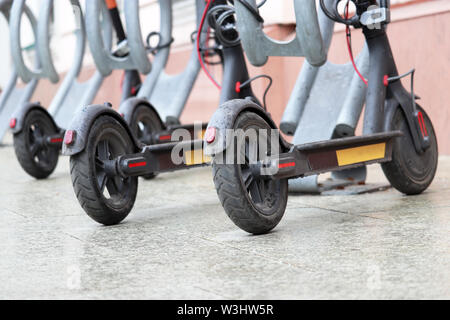 Scooter elettrici parcheggiato su una strada della citta'. Self-service di trasporto sistema di noleggio, e-scooter durante una pioggia Foto Stock