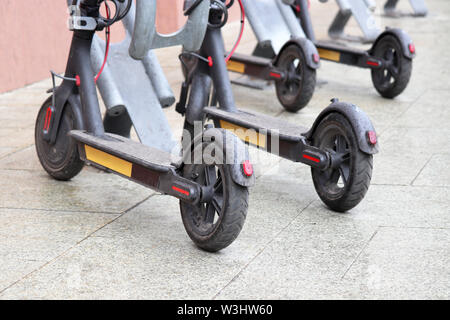 Scooter elettrici parcheggiato su un marciapiede. E-noleggio scooter, servizio tempo piovoso in una città Foto Stock