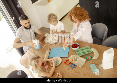 Famiglia unita. Vista dall'alto di un felice bella famiglia con bambini mentre la cucina insieme in cucina Foto Stock