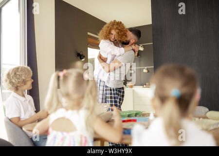 Matrimonio felice. Deliziati dai capelli rossi donna abbracciando il marito mentre è in amore con lui Foto Stock