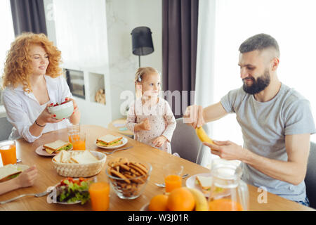 Deliziosa frutta. Gioioso uomo barbuto sorridere mentre sbucciare una banana in mano Foto Stock