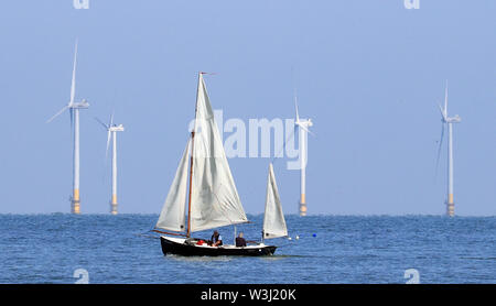 Una barca a vela passa il Kentish Flats Offshore Wind Farm durante il sole mattutino vicino a Herne Bay nel Kent. Foto Stock