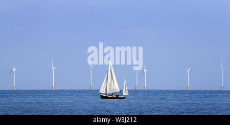 Una barca a vela passa il Kentish Flats Offshore Wind Farm durante il sole mattutino vicino a Herne Bay nel Kent. Foto Stock