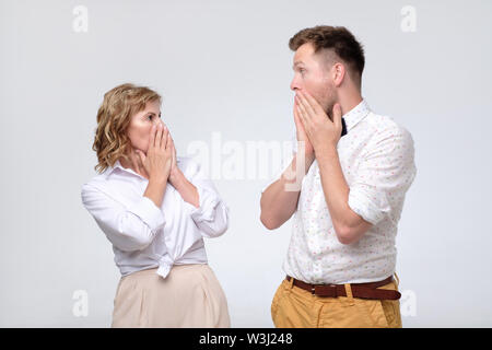 Sorpreso giovane uomo e donna matura guardando ogni altro in piena incredulità Foto Stock
