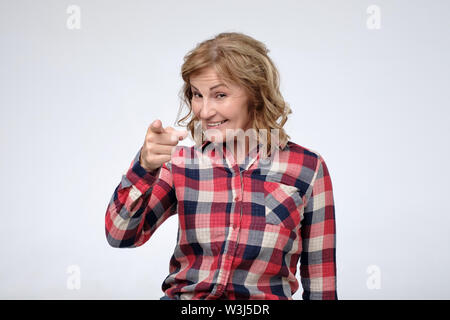 Matura donna caucasica indossando Camicia casual sorridente puntando alla fotocamera con le dita indice. Foto Stock