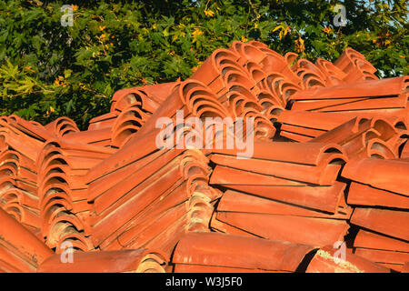 In cotto piastrelle di colore arancione da materiali naturali per il tetto. Curva di piastrelle di ceramica. Coperture di materiali di costruzione per la riparazione e costruzione di t Foto Stock