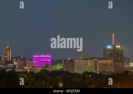 SYRACUSE, NEW YORK - Luglio 13, 2019: vista notturna del centro di Siracusa Cityscape con la Barclay Damon edificio e Axa torre in background. Foto Stock