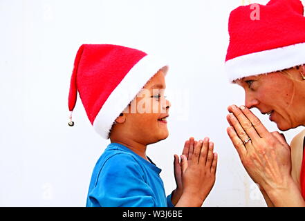 Madre e figlio che si divertono a Natale con cappelli di Natale foto stock su sfondo bianco Foto Stock