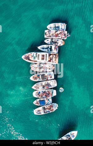 Scatto verticale in alto di imbarcazioni di varie dimensioni attraccate vicino a. l'un l'altro in una fila sull'acqua Foto Stock