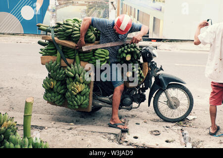 Vietnamita trasporto uomo molti banana bunch con la moto in Ho Chi Minh city il giorno, banane è popolare del prodotto di agricoltura in Vietnam Foto Stock