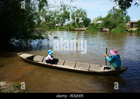 Vietnamita trasporto donna bambina andare a scuola per la barca di legno, figlia, madre sit squat per attraversare il fiume con bambù lungo al Vietnam campagna Foto Stock