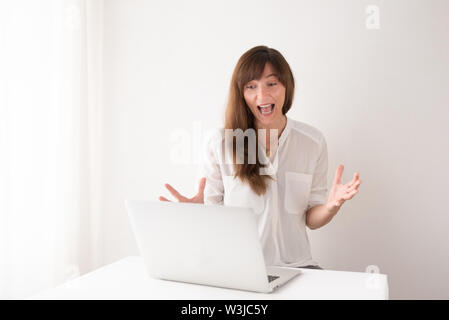 Bruna giovane donna con difficoltà tecniche con il suo computer portatile in ufficio Foto Stock