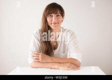 Ritratto di una bella bruna caucasian donna che indossa white contro uno sfondo bianco Foto Stock