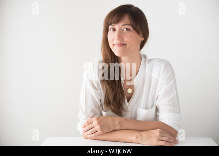 Ritratto di una bella bruna caucasian donna che indossa white contro uno sfondo bianco Foto Stock