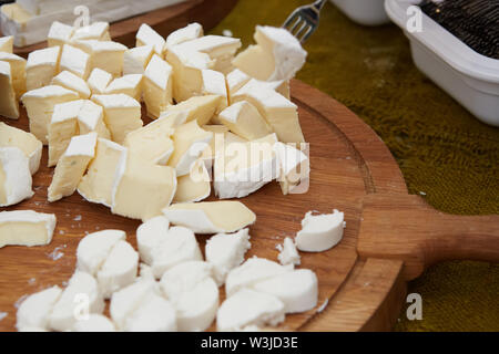 Chef cuoco di formaggio a fette su un tagliere. Gli ingredienti di taglio closeup Foto Stock