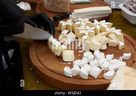 Chef cuoco di formaggio a fette su un tagliere. Gli ingredienti di taglio closeup Foto Stock