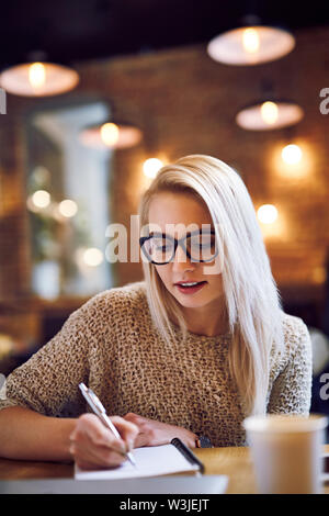 Giovane donna studia da caffè durante la pausa caffè Foto Stock