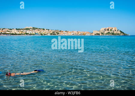 Un irriconoscibile la persona immersioni in Mar mediterraneo a la Plage de Calvi beach, in Calvi, Corsica, Francia, con la sua famosa cittadella del bac Foto Stock